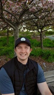 Collin smiling under a cherry blossom tree